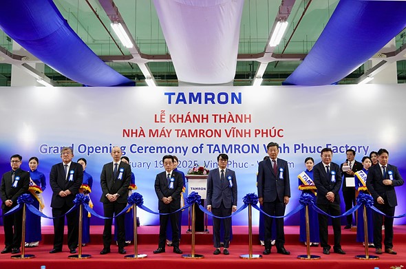 group of people with ribbons stand in fonrt of sign for tamron ceremony