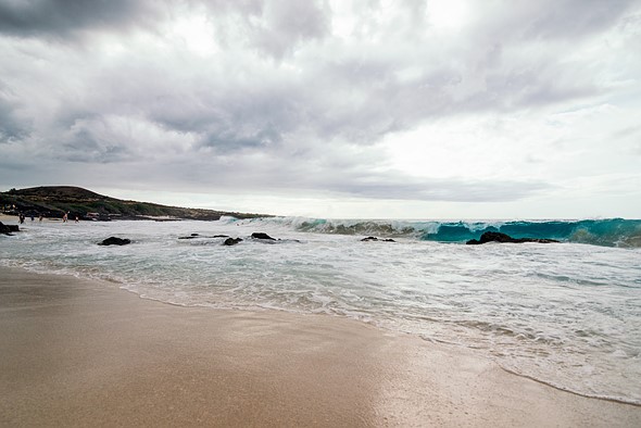 a wave crashes into a white sandy beach