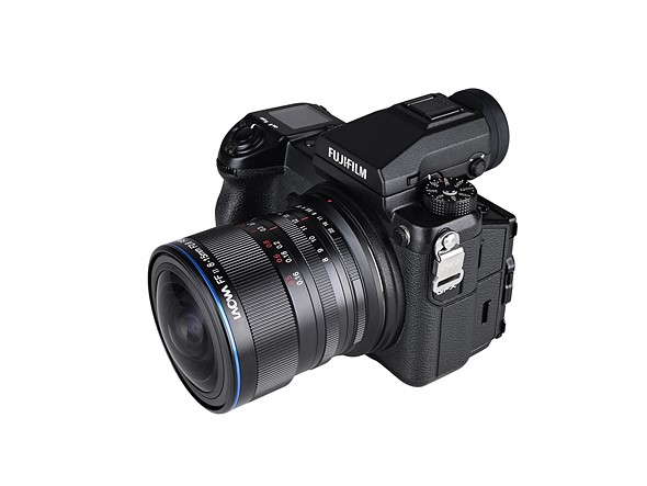 a black fujifilm camera has a laowa lens attached while on a white background