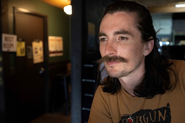 Portrait of a young man with long hair and moustache in reflected sunlight.acr