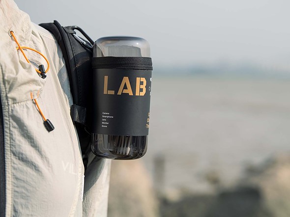a dark clear canister is clipped onto a backpack shoulder strap