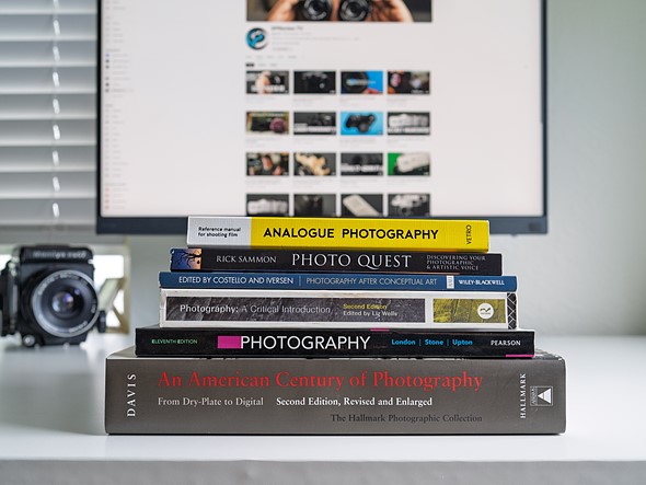 a stack of books sits on a white desk in front of a monitor