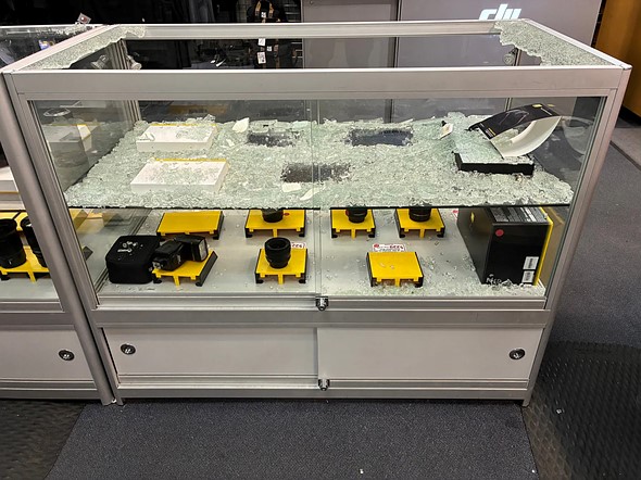 a shattered glass display case with missing camera gear sits in a store