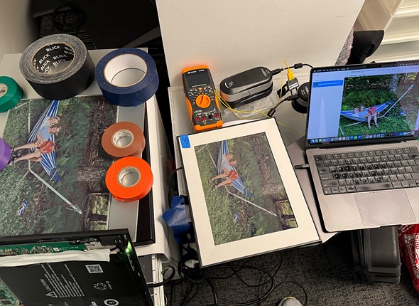 a mess of tape rolls prints displays laptop tools and more clutter a workspace