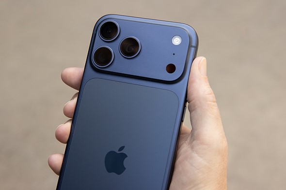 The back of a blue iPhone 17 Pro Max held in a hand showing the cameras and Apple logo