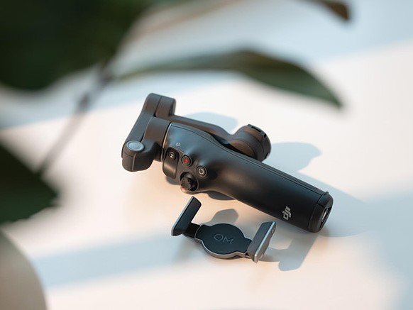 the osmo mobile 8 gimbal and phone mount are on a white table with a plant in front