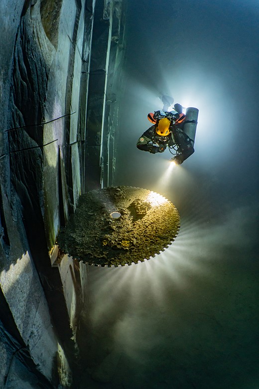 a diver shines a light at a mining site underwater