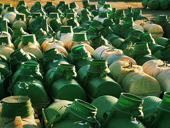 green and white plastic jugs are lined up on a dirt roadside