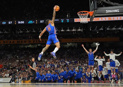 a person jumps to dunk in a cgym crowded with fans