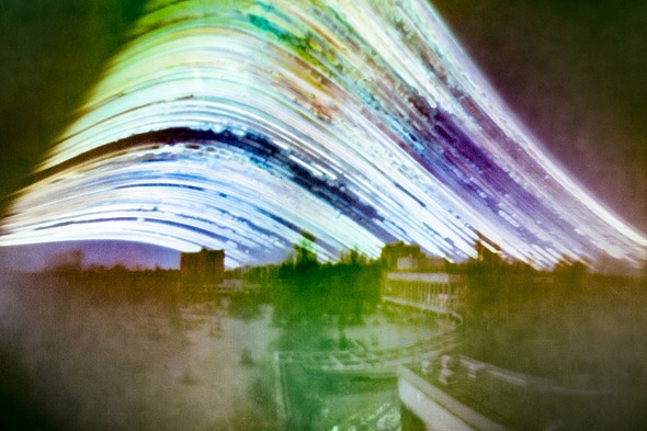 colorful streaks of light curve above a blurred cityscape