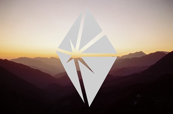 A light gray diamond-shaped logo over a mountain scene washed in orange sunet light